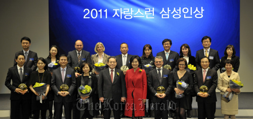 Samsung chairman Lee Kun-hee (fifth from left, front row) and his wife Hong Ra-hee (fifth from right, front row) pose with seven Samsung executives and two chiefs of the group’s partner firms, as well as their family members, after the nine were named this year’s Samsung fellows at a ceremony in southern Seoul on Thursday.    Samsung Group