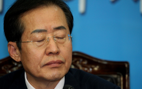 <YONHAP PHOTO-1025> 유구무언 (서울=연합뉴스) 백승렬 기자 = 한나라당 홍준표 대표가 7일 오전 한나라당 최고위원 3명의 동반사퇴 표명 후 당사에서 자신의 거취를 표명하는 기자회견에서 굳은 표정으로 앉아 있다. 2011.12.7 srbaek@yna.co.kr/2011-12-07 12:48:47/ <저작권자 ⓒ 1980-2011 ㈜연합뉴스. 무단 전재 재배포 금지.>
Rep. Hong Joon-pyo, chair of the Grand National Party, pauses during a news conference at the National Assembly on Wednesday.  Yonhap News