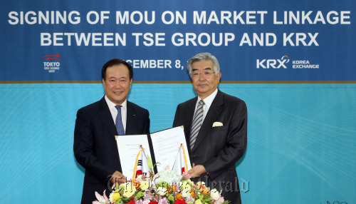 Korea Exchange CEO Kim Bong-soo (left) and Tokyo Stock Exchange Group CEO Atsushi Saito pose at the KRX headquarters in Seoul on Thursday after signing a memorandum of understanding for bilateral cooperation that includes the cross trades of stocks, ETF listing and market data sharing.   Yonhap News