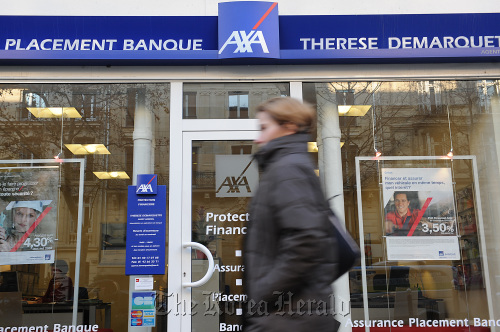 A pedestrian passes an Axa SA branch in Paris.  Bloomberg