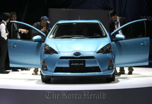 Visitors look at a Toyota Motor Corp. Aqua hybrid vehicle at the Tokyo Motor Show 2011 in Tokyo. Toyota delayed the new projections by a month because of the floods.     Bloomberg