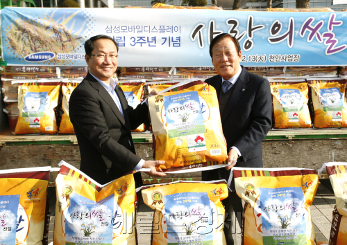 삼성모바일디스플레이가 13일 대형 트럭 31대 분량에 달하는 쌀 140t을 사업장 주변 도움이 필요한 이웃에게 전달하는 ‘쌀 나눔’ 행사를 가진 가운데 조수인(왼쪽) 사장이 충남 천안시청에서 성무용 천안시장에게 사랑의 쌀을 기증하고 있다.