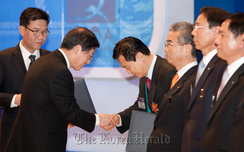 Prime Minister Kim Hwang-sik (left) shakes hands with WOORY Industrial Company CEO Kim Myung-joon at an awarding ceremony for the 37th Korea National Quality Awards held in COEX, southern Seoul, on Tuesday.   KSA