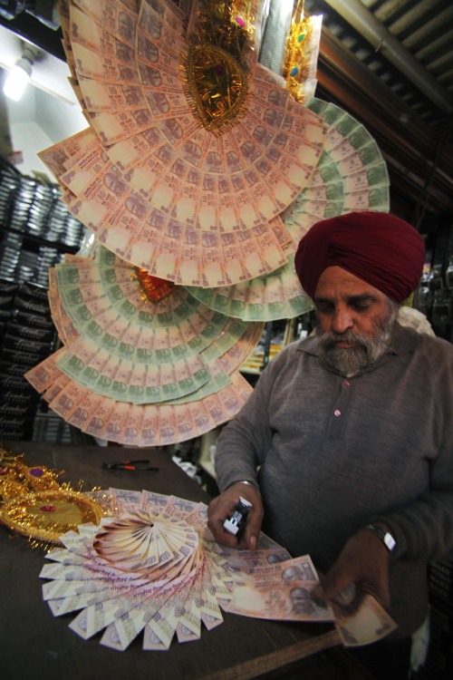 <YONHAP PHOTO-2798> A vendor makes a garland with Indian 10 rupee currency for sale in Jammu, India, Wednesday, Dec. 14, 2011. In India currency garlands are used to felicitate individuals at public functions as well as at some weddings for the groom. The plunging value of the rupee, which hit a fresh record low against the dollar Wednesday, is pushing up the cost of fuel and manufactured products even as big increases in food prices start to wane, government figures showed. (AP Photo/Channi Anand)/2011-12-14 22:44:03/ <저작권자 ⓒ 1980-2011 ㈜연합뉴스. 무단 전재 재배포 금지.>\r\n<YONHAP PHOTO-2798> A vendor makes a garland with Indian 10 rupee currency for sale in Jammu, India, Wednesday, Dec. 14, 2011. In India currency garlands are used to felicitate individuals at public functions as well as at some weddings for the groom. The plunging value of the rupee, which hit a fresh record low against the dollar Wednesday, is pushing up the cost of fuel and manufactured products even as big increases in food prices start to wane, government figures showed. (AP Photo/Channi Anand)/2011-12-14 22:44:03/ <저작권자 ⓒ 1980-2011 ㈜연합뉴스. 무단 전재 재배포 금지.>