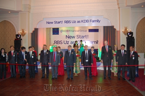 KDB Financial Group chairman Kang Man-soo (sixth from left, front row) poses at an event to celebrate the group’s acquisition of RBS Uz at a hotel in Tashkent, Uzbekistan, on Wednesday. Participants included RBS Uz CEO Kwak Yong-kyu (second from left, front row) and Uzbek Deputy Finance Minister Mubin Mirzaev (fifth from left, front row).    KDB