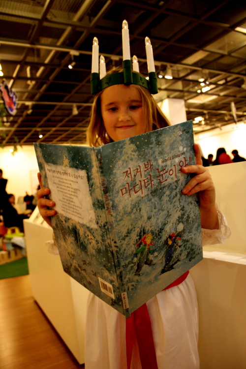 A Swedish girl in a Lucia Train outfit holds a Swedish book translated into Korean at the National Library of Children and Young Adults in Seoul on Thursday. (Kirsty Taylor/The Korea Herald)