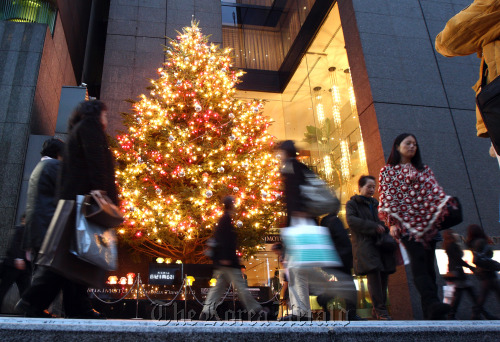 Shoppers walk past an illuminated Christmas tree in Tokyo.  Bloomberg
Shoppers walk past an illuminated Christmas tree in Tokyo.  Bloomberg