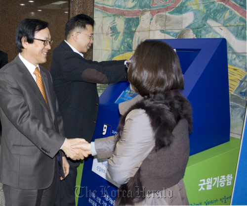Export-Import Bank of chairman & CEO Kim Yong-hwan (left) shakes hands with a representative of Korea Goodwill after donating a bundle of clothes to the social activities center in southern Seoul on Dec. 12.      Korea Eximbank