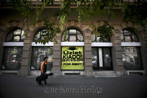 A pedestrian walks past shop premises advertised for rent in Budapest, Hungary.  Bloomberg