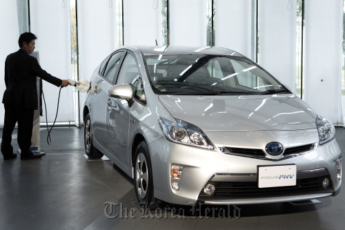 An employee demonstrates the charging of Toyota Motor Corp.’s Prius plug-in hybrid vehicle during the unveiling in Tokyo.   Bloomberg