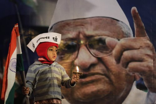 <YONHAP PHOTO-0758> A young supporter of Indian anti-corruption activist Anna Hazare, depicted in photograph in background, wears a cap that reads "I am Anna" as he hold the Indian flag during a protest against corruption in Ahmadabad, India, Tuesday, Dec. 27, 2011. Indian lawmakers fiercely debated sweeping anti-corruption legislation Tuesday while Hazare began a three-day hunger strike demanding Parliament adopt his tougher proposals. (AP Photo/Ajit Solanki)/2011-12-28 13:56:42/ <저작권자 ⓒ 1980-2011 ㈜연합뉴스. 무단 전재 재배포 금지.>
A young supporter of Indian anti-corruption activist Anna Hazare, depicted in the background, wears a cap that reads “I am Anna” as he hold the Indian flag during a protest against corruption in Ahmadabad, India, Tuesday.  AP-Yonhap News