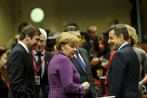 Left to right, Pedro Passos Coelho, Portugal’s prime minister, Angela Merkel, Germany’s chancellor, and Nicolas Sarkozy, France’s president, speak ahead of the summit of European Leaders at the European Council headquarters in Brussels on Dec. 9.  Bloomberg