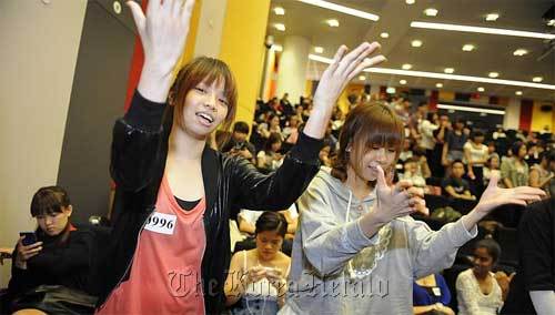Students Evenie Liu (left) and Melodie Pok, both 20, rehearse their dance moves while waiting their turn at the audition.  The Straits Times