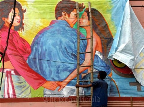 A movie theater worker removes a poster of the Bollywood film “Girlfriend,” a film about a lesbian couple, after Hindu hard-liners demanded a ban on the film, in Allahabad, India in 2004.  AP-Yonhap News