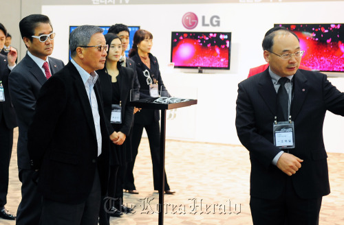 LG Group chairman Koo Bon-moo (second from left) is briefed by a company executive on the electronic firm’s 55-inch OLED TV to be released soon on Friday.    Yonhap News