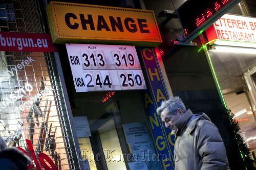 A pedestrian passes a currency exchange store advertising forint exchange rates with euros and dollars in central Budapest.  Bloomberg