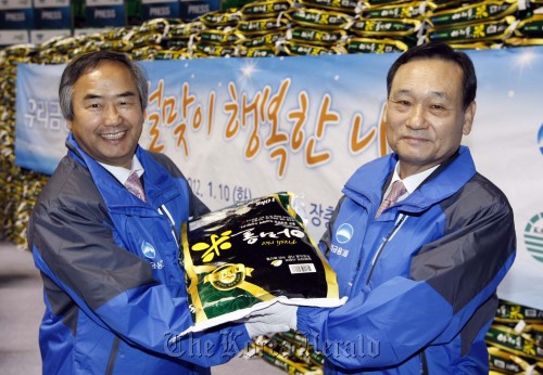 Woori Financial Group chairman Lee Pal-seung (right) poses after donating 3,500 bags of rice to the Korea Association of Social Welfare Centers on Tuesday as part of the group’s social activities ahead of the Lunar New Year holiday.    Woori Financial