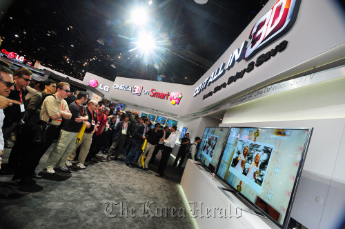 Visitors look at LG Electronics’ new smart TV sets in CES on Thursday. LG Electronics