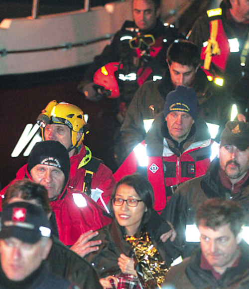 View of the Costa Concordia taken on saturday after the cruise ship ran aground and keeled over off the isola del giglio, italy. (AFP-Yonhap News)
A passenger (front center) from Korea walks with italian firefighters after being rescued from the luxury cruise ship Costa Concordia, which ran aground the tiny Tuscan island of giglio, italy, sunday. (AP-Yonhap News)
