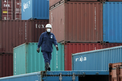 A man walks on a container at a shipping terminal in Tokyo.  Bloomberg