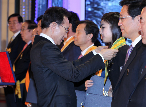 <YONHAP PHOTO-1322> 훈장 받는 김연아 (평창=연합뉴스) 진성철 기자 = 이명박 대통령이 17일 강원도 평창군 대관령면 용평돔경기장에서 열린 평창동계올림픽 성공개최 범국민 다짐대회에서 2018평창동계올림픽유치위 홍보대사로 활약했던 '피겨 여왕' 김연아에게 국민훈장 모란장을 수여하고 있다. 2012.1.17 zjin@yna.co.kr/2012-01-17 15:40:55/ <저작권자 ⓒ 1980-2012 ㈜연합뉴스. 무단 전재 재배포 금지.>
President Lee Myung-bak presents a medal to Kim Yu-na during a special rally for the 2018 Olympics in PyeongChang, Gangwon Province on Tuesday.  Yonhap News