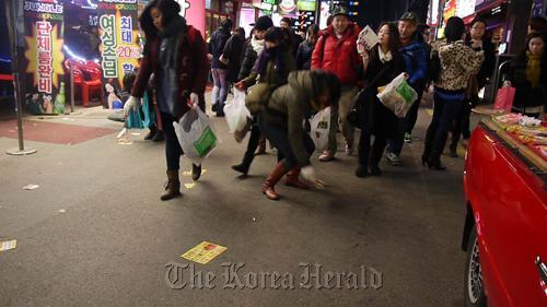 Expats pick up fliers soliciting sexual services during an anti-prostitution flash mob.    Elysabeth Hahm