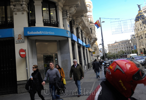 Pedestrians pass a Banco Sabadell SA bank branch in Madrid.  Bloomberg