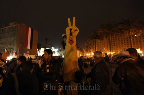 <YONHAP PHOTO-0292> An Egyptian protester paints on a sculpture of a hand making a victory sign while others gather at Tahrir Square in preparation to mark the first anniversary of the revolution Wednesday, in Cairo, Egypt Tuesday Jan. 24, 2012. Egypt's military ruler on Tuesday decreed a partial lifting of the nation's hated emergency laws, an apparent attempt to ease criticism of his policies ahead of the first anniversary of the popular uprising that toppled Hosni Mubarak. (AP Photo/Khalil Hamra)/2012-01-25 04:48:32/ <저작권자 ⓒ 1980-2012 ㈜연합뉴스. 무단 전재 재배포 금지.>
An Egyptian protester paints on a sculpture of a hand making a victory sign at Tahrir Square in Cairo, Tuesday. AP-Yonhap News