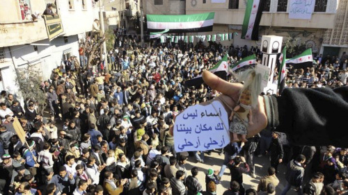 A demonstrator holds up a toy reading "Asma, wife of Syria's Assad, no place for you between us, leave" during a protest against Syria's President Bashar al-Assad after Friday prayer in Talbiseh near Homs February 3, 2012. REUTERS-Yonhap