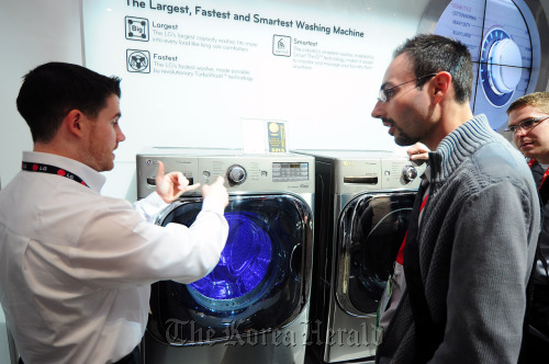 An LG official explains the company’s drum washer to a visitor at the 2012 Consumer Electronics Show in Las Vegas in January.  Yonhap News