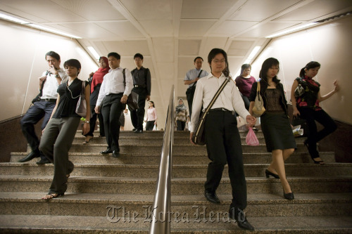 Office workers arrive for work in the central business district of Singapore.  Bloomberg