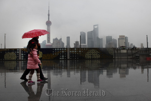 Pedestrians walk near the Lujiazui Financial District in the distance in Shanghai.  Bloomberg