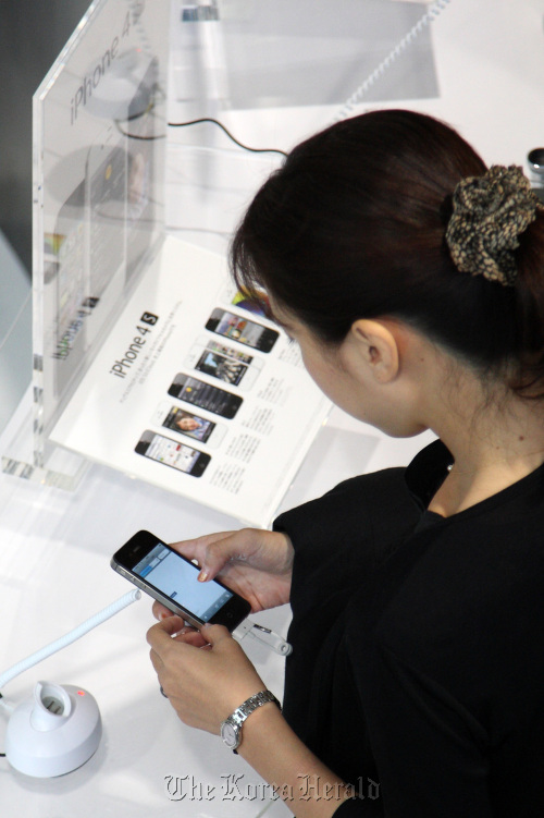 A customer tries an Apple Inc. iPhone 4S at a KDDI Corp. shop in Tokyo.  Bloomberg
A customer tries an Apple Inc. iPhone 4S at a KDDI Corp. shop in Tokyo.  Bloomberg