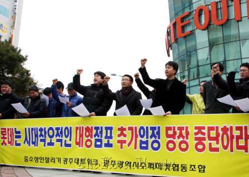 Members of groups representing small vendors and non-franchise supermarkets rally against the establishment of new discount stores in front of a Lotte Mart on Tuesday in Gwangju. Yonhap News