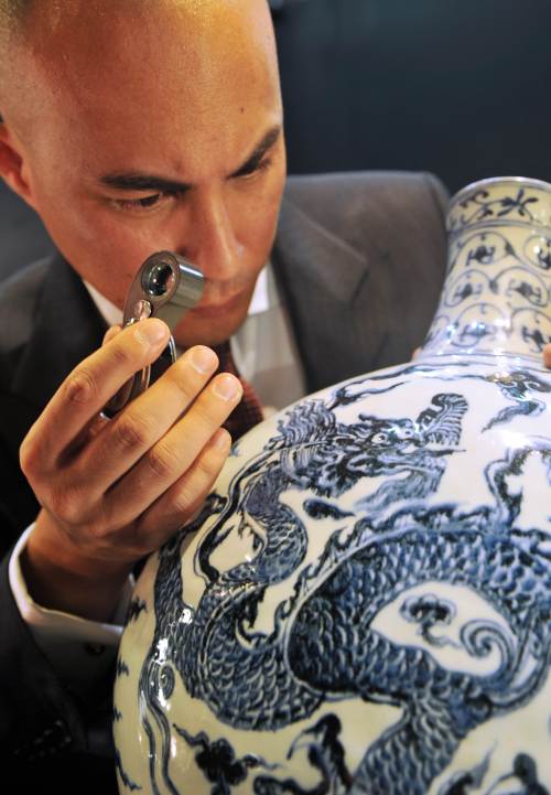 <YONHAP PHOTO-1303> TO GO WITH HongKong-China-antiquity-copyright-auction-fraud by Peter Brieger This photo taken on September 30, 2011 shows the head of Sotheby's Chinese Ceramics Department, Nicolas Chow, checking a Ming Dynasty blue and white vase with fruit sprays in Hong Kong. The demand for Chinese antiquities has exploded, helping propel Hong Kong to third spot in the global auction market behind London and New York as collectors slap down eye-popping sums for a piece of the country's history. AFP PHOTO / LAURENT FIEVET /2012-02-07 14:41:09/ <저작권자 ⓒ 1980-2012 ㈜연합뉴스. 무단 전재 재배포 금지.>
This photo taken on Sept. 30 shows the head of Sotheby’s Chinese Ceramics Department, Nicolas Chow, checking a Ming Dynasty blue and white vase with fruit sprays in Hong Kong.  AFP-Yonhap News
