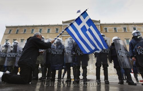 An anti-austerity protester waves a Greek flag in front of the heavily guarded parliament in Athens Feb. 7, 2012. (Reuters-Yonhap News)