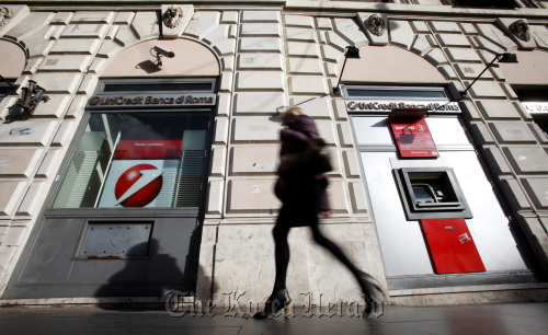A pedestrian passes a branch of the UniCredit SpA bank in Rome.  Bloomberg