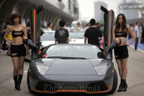 Models pose with a Lamborghini SpA sports car during the Shanghai International Circuit Club Challenge in Shanghai.  Bloomberg