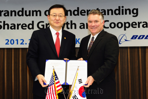 Knowledge Economy Minister Hong Suk-woo (left) and Boeing Korea president Pat Gaines pose after signing an agreement for collaboration between Korean firms and the U.S. aerospace company on developing parts and materials for aircraft at a ceremony in Seoul on Wednesday.  MKE