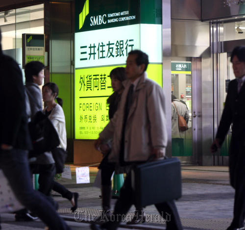 Pedestrians walk past a Sumitomo Mitsui Banking Corp. branch in Tokyo.  Bloomberg