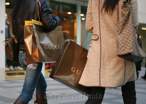 Two women carrying shopping bags from Gucci walk down the street in Shanghai.  Bloomberg