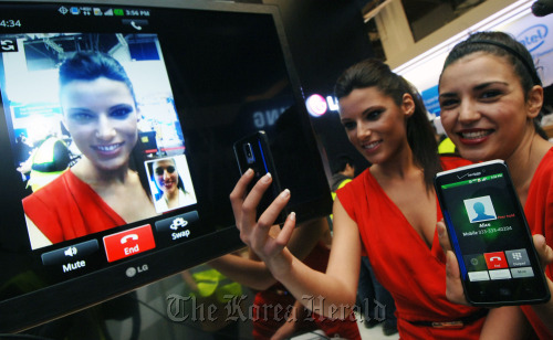 Models make video calls on LG Electronics’ Optimus LTE smartphone on Monday at the Mobile World Congress being held on the showroom floor of the Fira de Barcelona.  LG Electronics