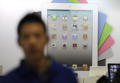 A salesman stands in front of an Apple Ipad advertisement board at an Apple store in Beijing last Wednesday. (AFP-Yonhap News)