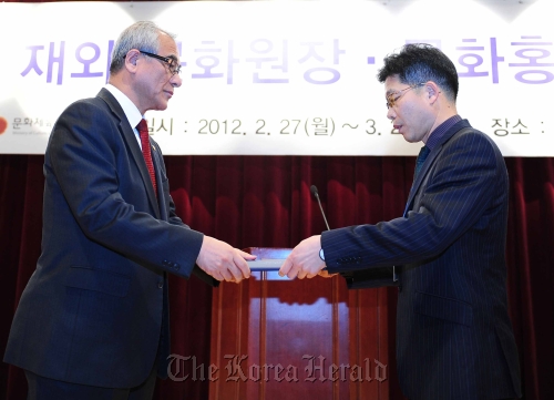 Won Yong-gi (right), the director of KCC in London, receives a prize from Culture Minister Choe Kwang-shik on Monday in Seoul.  Ministry of Culture, Sport and Tourism