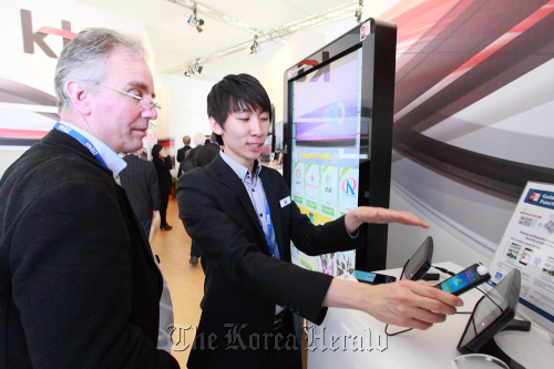 A KT employee explains the new near field communication roaming coupon service to a visitor at the Mobile World Congress in Barcelona on Tuesday. KT Corp.