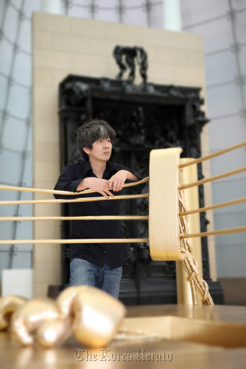 Bae Young-whan poses with his work “Golden Ring ― A Beautiful Hell.”  Plateau