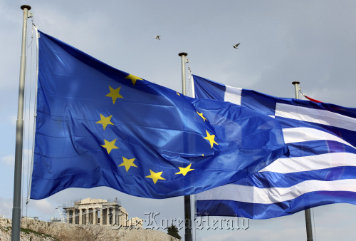 A European Union flag (left) and Greek national flag fly near the Parthenon temple on Acropolis hill in Athens.  Bloomberg