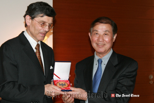 German Ambassador Hans-Ulrich Seidt presents a medal to press officer Doe Phil-young at a dinner held to mark his 40 years of service to the German Embassy on Monday.  Seoul Times