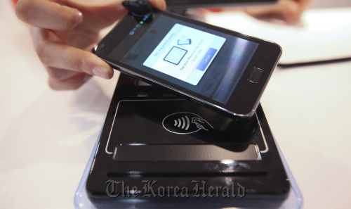 An employee demonstrates the use of a smartphone with an NFC-enabled tagging point for wireless payment at the Mobile World Congress in Barcelona last week.  MCT