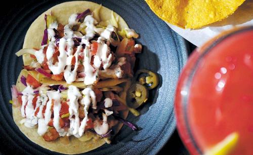 Chili lime shrimp tacos, a popcorn shrimp-meets-coleslaw-style concoction that has been amped up by chipotle, and a strawberry makgeolita, at Vatos Urban Tacos. (Park Hae-mook/The Korea Herald)